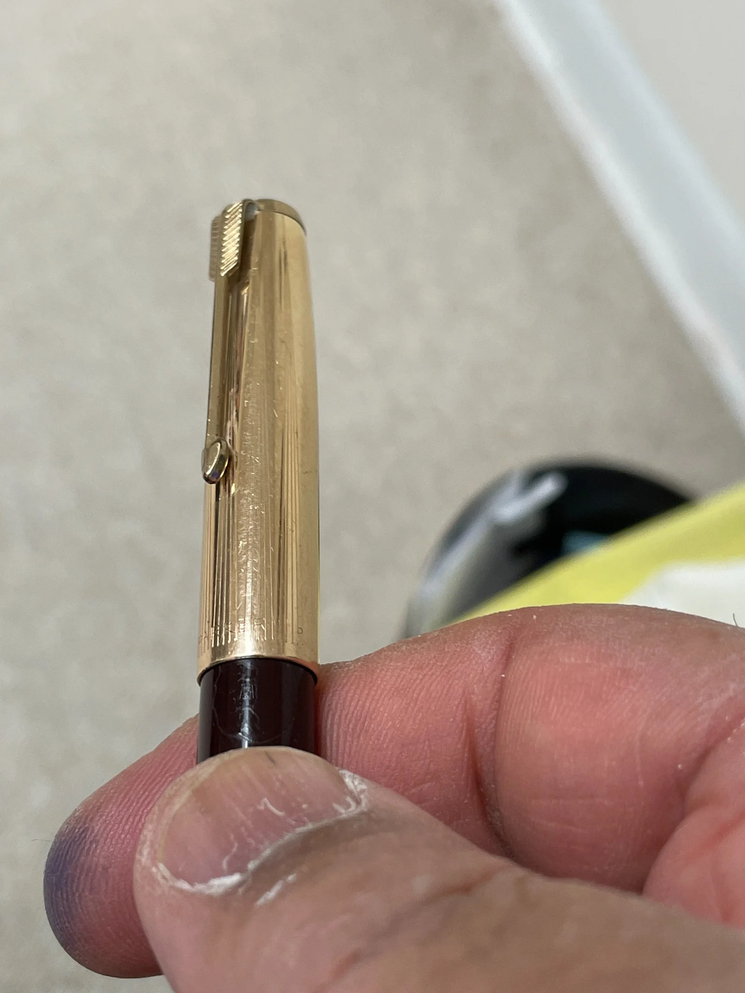 Close-up of a gold-tone writing instrument cap, clip and engraved barrel detail